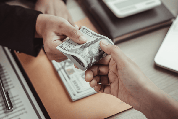 Close-up of hands exchanging cash in an office, symbolizing strategic withdrawals and income planning for tax-efficient retirement