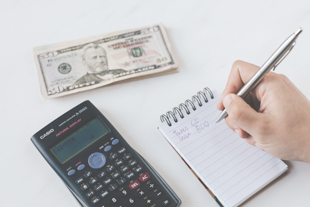 Person writing financial goals on a notepad with cash and calculator, symbolizing indexed universal life (IUL) insurance retirement planning strategy